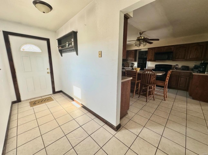 Foyer featuring light tile patterned floors, baseboards, and a ceiling fan