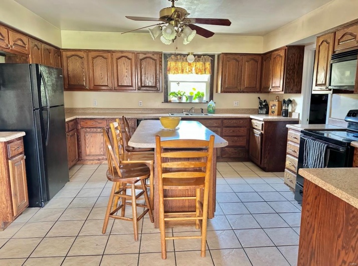 Kitchen featuring light countertops, a sink, black appliances, and ceiling fan