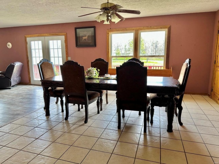 Dining space featuring light tile patterned flooring, a textured ceiling, and ceiling fan