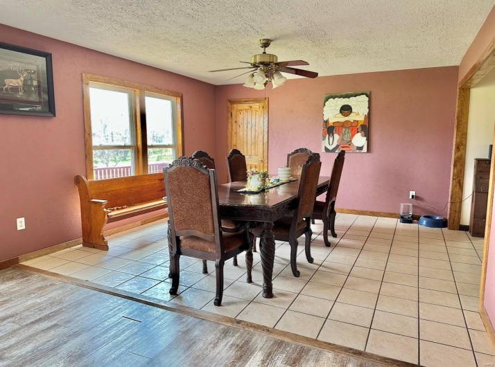 Dining room with light wood-style floors, a textured ceiling, baseboards, and ceiling fan