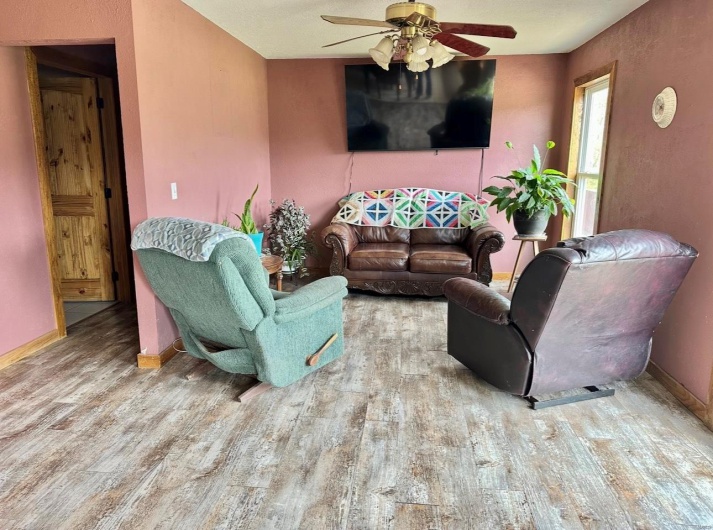 Living room featuring baseboards, a ceiling fan, and wood finished floors