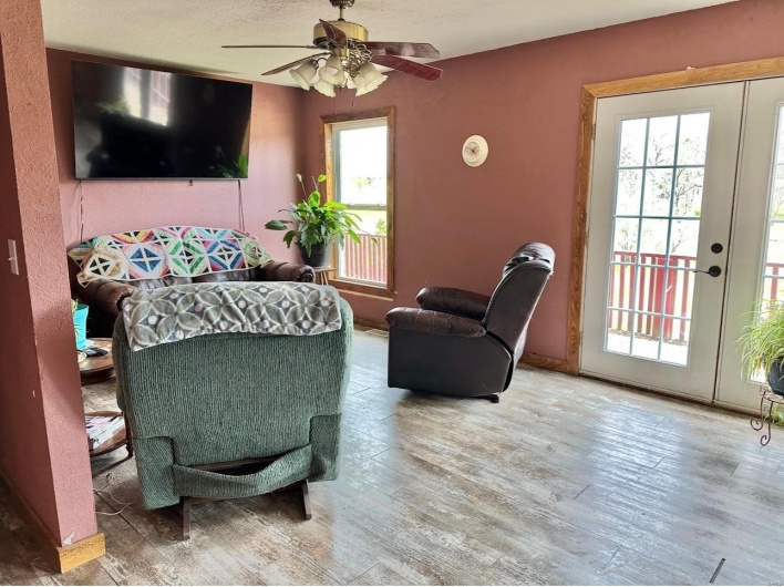 Living room featuring a ceiling fan, wood finished floors, and a healthy amount of sunlight