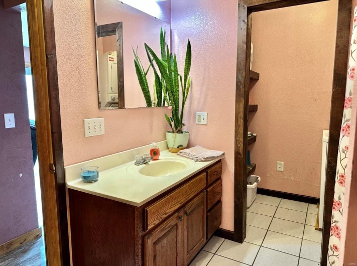 Bathroom with a textured wall, tile patterned flooring, and vanity