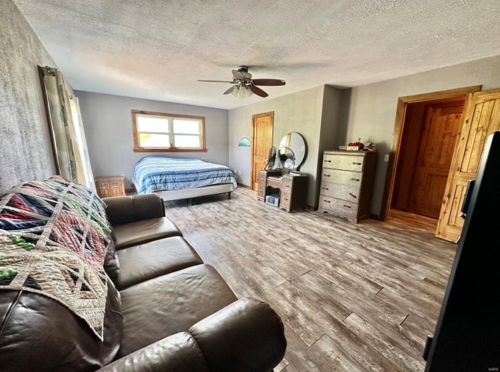 Bedroom with a textured ceiling, a ceiling fan, and wood finished floors