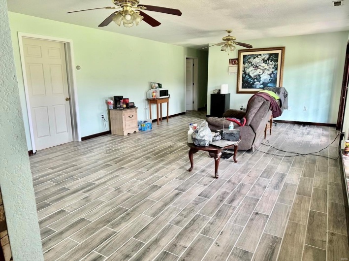 Living room with wood finished floors, baseboards, a ceiling fan, and visible vents