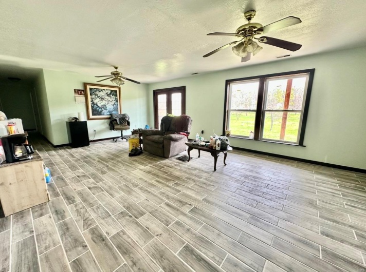 Living room featuring a textured ceiling, wood finished floors, ceiling fan, and baseboards