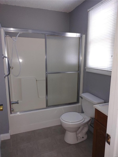 Full bathroom featuring vanity, toilet, and enclosed tub / shower combo