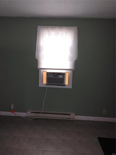 Unfurnished room featuring dark parquet flooring, cooling unit, a baseboard radiator, and a textured ceiling