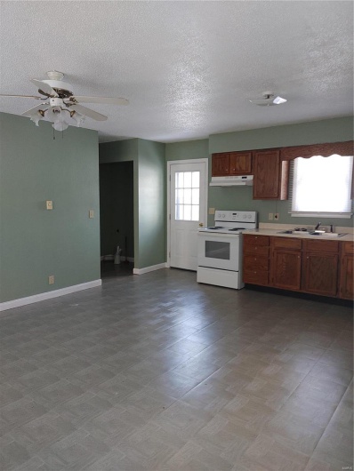 Kitchen featuring ceiling fan, sink, ventilation hood, a textured ceiling, and range