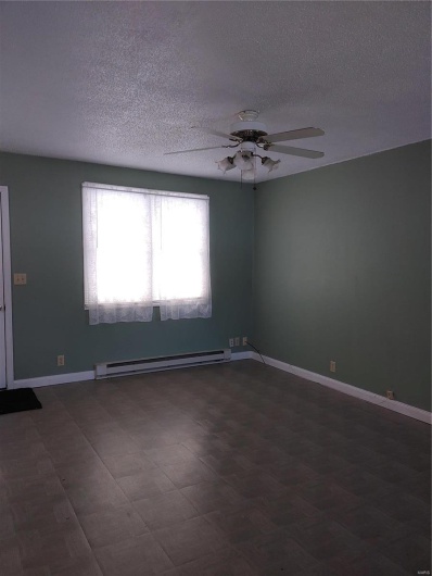Empty room featuring baseboard heating, ceiling fan, and a textured ceiling