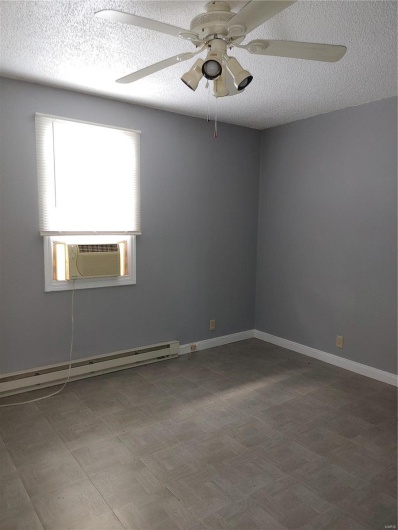 Empty room with baseboard heating, ceiling fan, cooling unit, and a textured ceiling