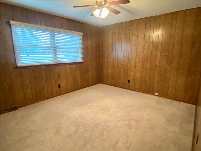 Carpeted empty room with ceiling fan and wood walls