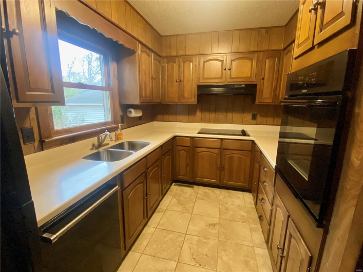 Kitchen featuring a textured ceiling, sink, white stovetop, dishwasher, and black oven