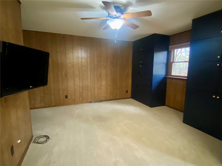 Interior space with ceiling fan and wood walls