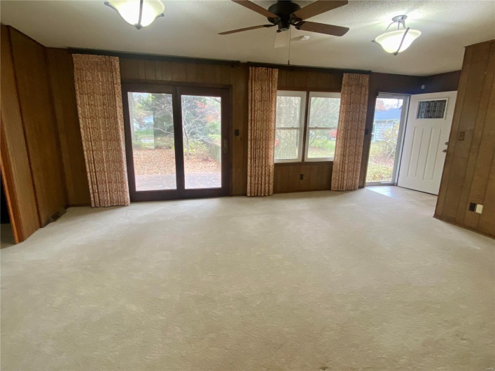 Unfurnished room with ceiling fan, light carpet, and wooden walls