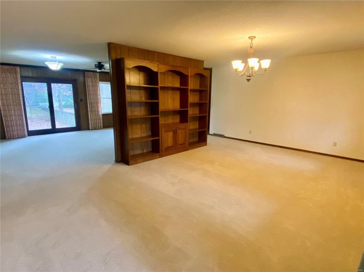 Carpeted empty room featuring a chandelier