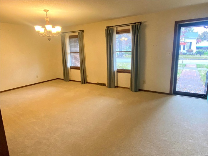 Empty room featuring light carpet and an inviting chandelier