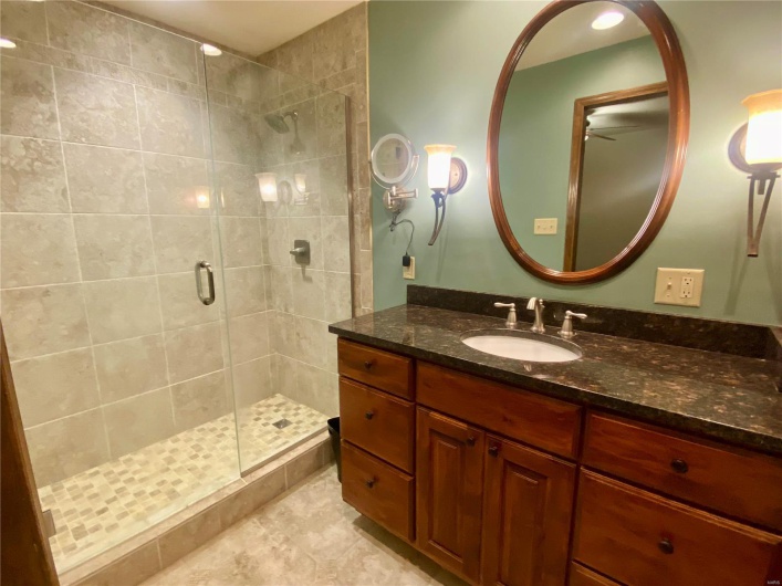 Bathroom with ceiling fan, a shower with shower door, and vanity