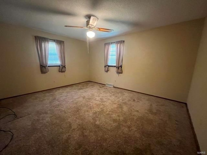 Empty room featuring ceiling fan, carpet, and a healthy amount of sunlight