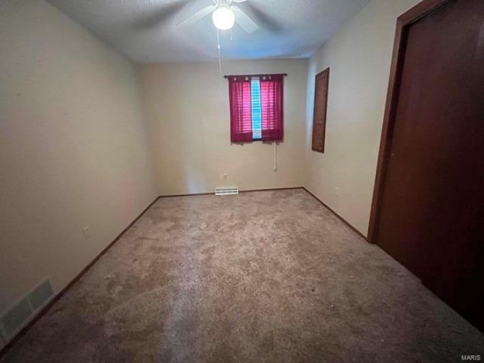 Carpeted spare room with a ceiling fan and visible vents