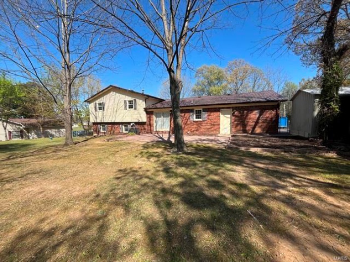 Back of property with a storage shed, an outdoor structure, and a lawn