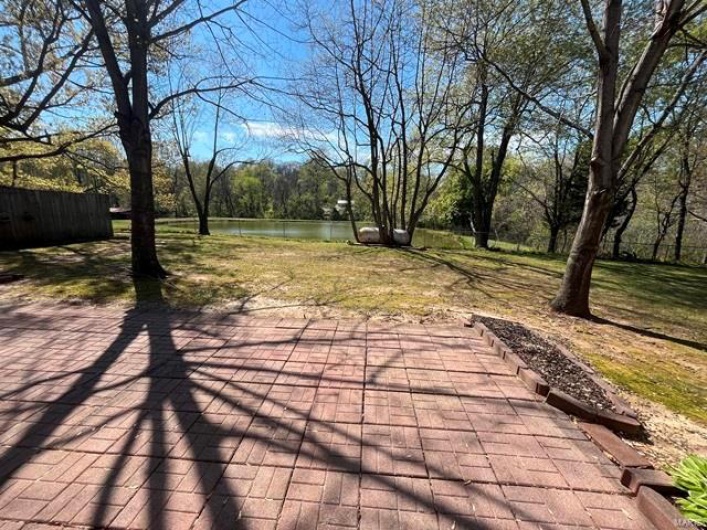 View of patio featuring a water view and fence
