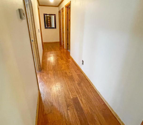 Hall with ornamental molding, light wood-style flooring, and baseboards