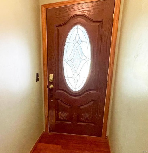 Doorway with baseboards and wood finished floors