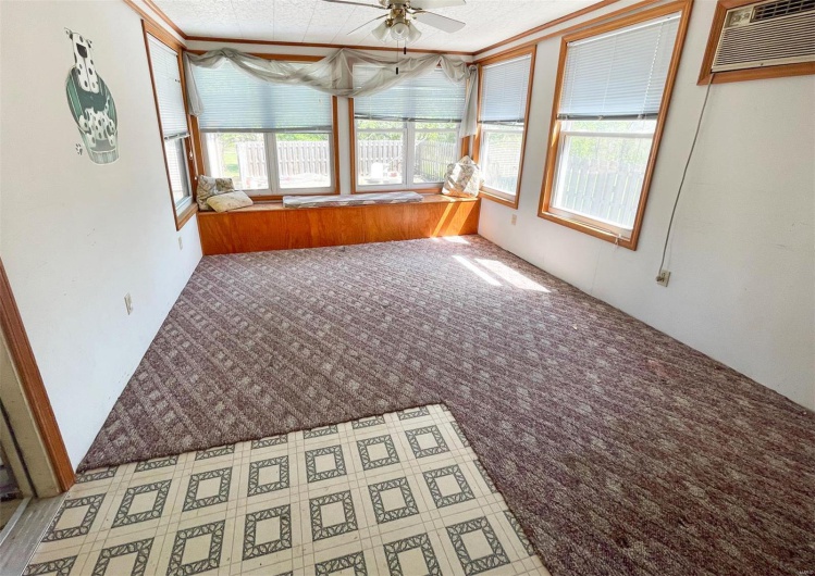 Unfurnished sunroom with carpet flooring and an AC wall unit