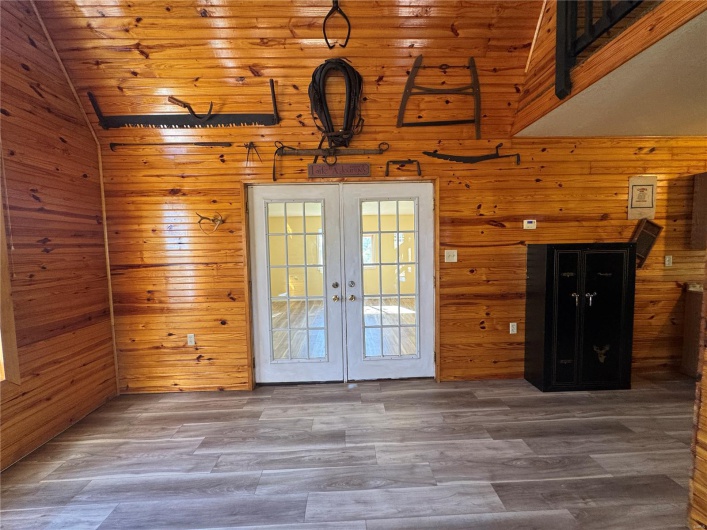 Doorway featuring french doors, wooden walls, lofted ceiling, and wood finished floors