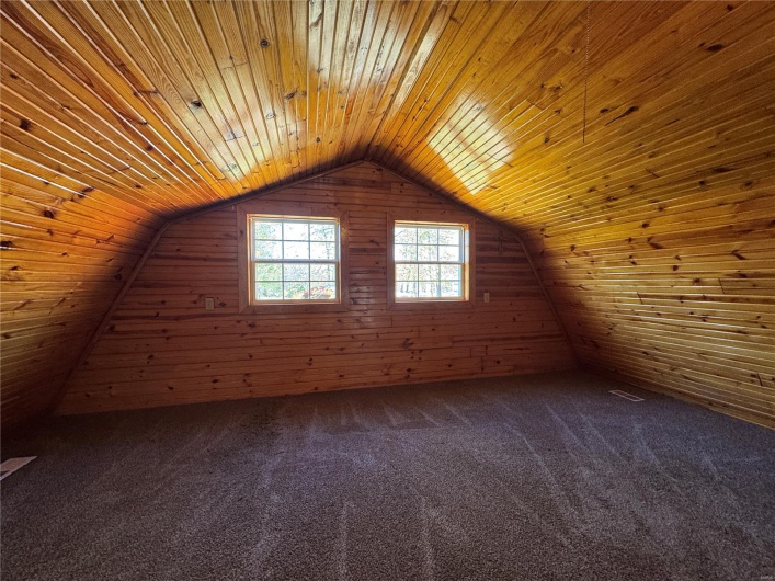 Bonus room featuring wood ceiling, wood walls, dark colored carpet, and vaulted ceiling