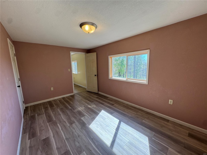 Spare room featuring a textured ceiling, baseboards, and wood finished floors