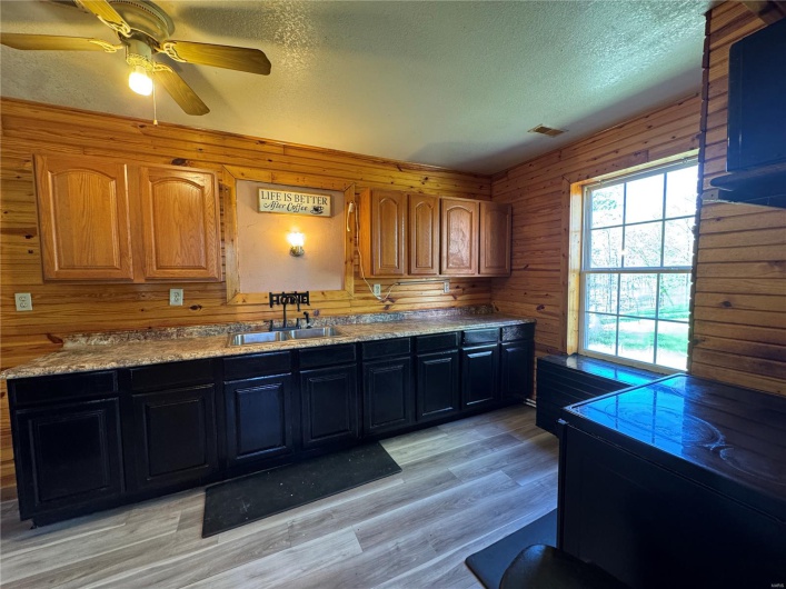 Kitchen with a sink, wood walls, and a textured ceiling