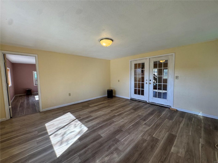 Empty room featuring dark wood-type flooring, french doors, and baseboards