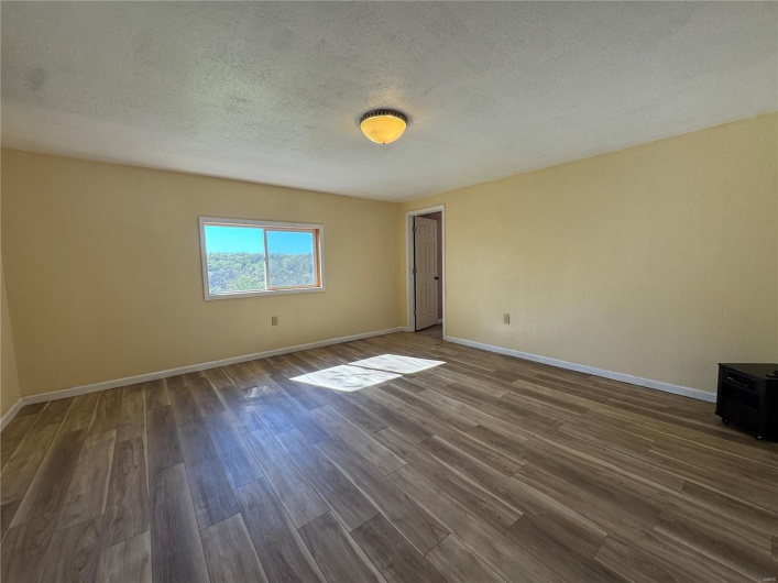 Spare room featuring dark wood-style floors, baseboards, and a textured ceiling