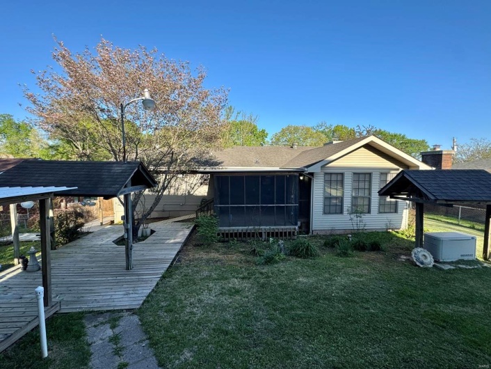 Back of property with a sunroom and a lawn