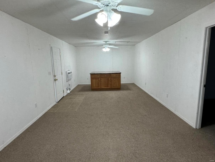 Spare room with baseboards, a ceiling fan, heating unit, and carpet