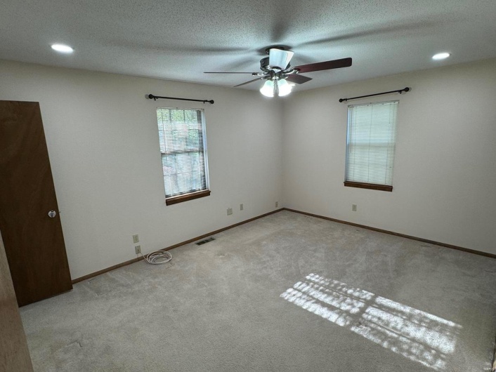 Unfurnished room with ceiling fan, carpet, a textured ceiling, visible vents, and baseboards
