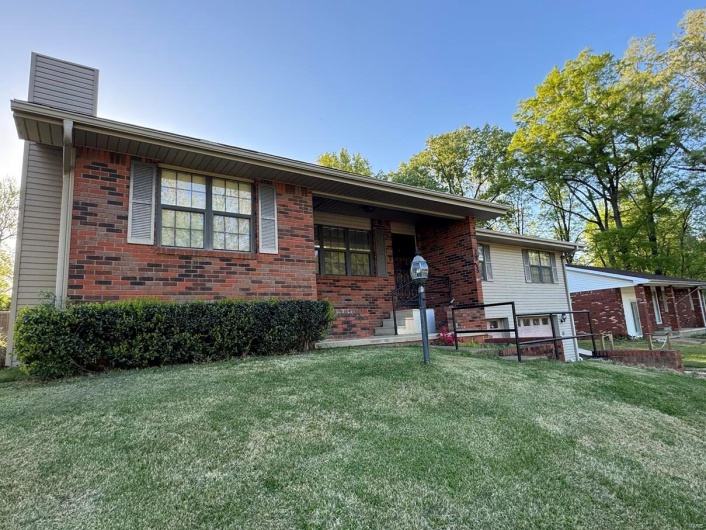 View of front of house featuring brick siding, a chimney, and a front lawn