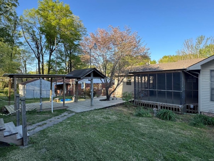 View of yard featuring a wooden deck and a sunroom