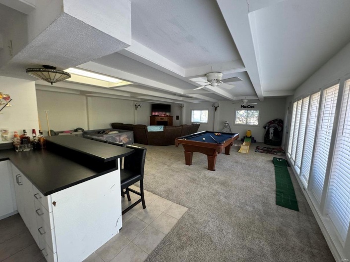 Game room featuring light tile patterned floors, beamed ceiling, a ceiling fan, light carpet, and billiards