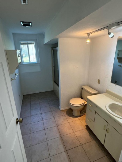 Bathroom with vanity, tile patterned flooring, toilet, bath / shower combo with glass door, and baseboards
