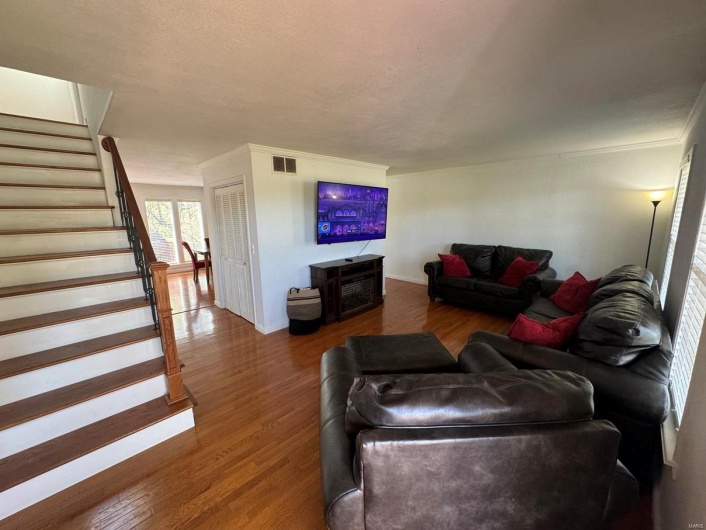 Living room featuring wood finished floors, visible vents, and stairway