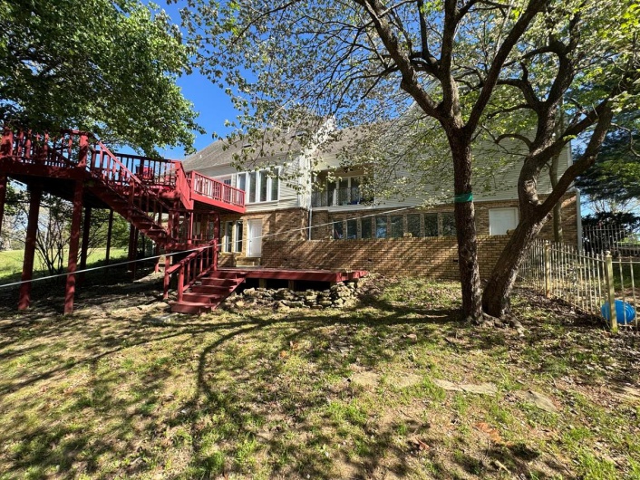 Back of property featuring stairs, a yard, a wooden deck, and fence
