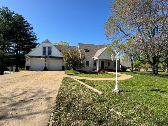 View of front of property with concrete driveway, a front yard, and an attached garage