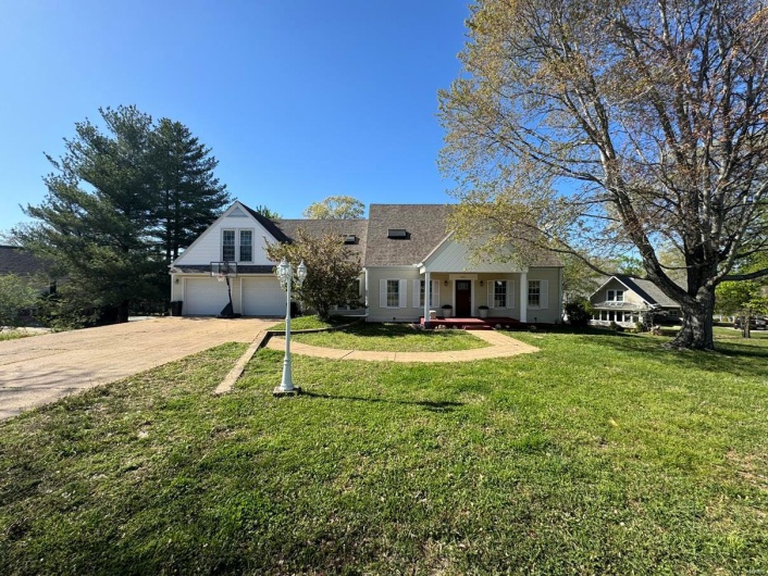 View of front of home with a front yard, a shingled roof, a garage, and concrete driveway