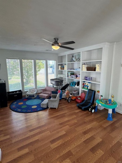 Rec room featuring ceiling fan, wood finished floors, and built in shelves