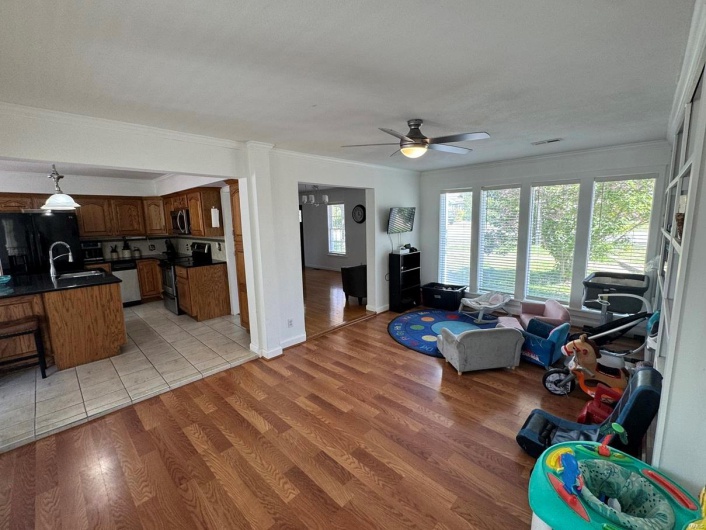 Living area featuring light wood-style floors, ceiling fan, ornamental molding, and visible vents