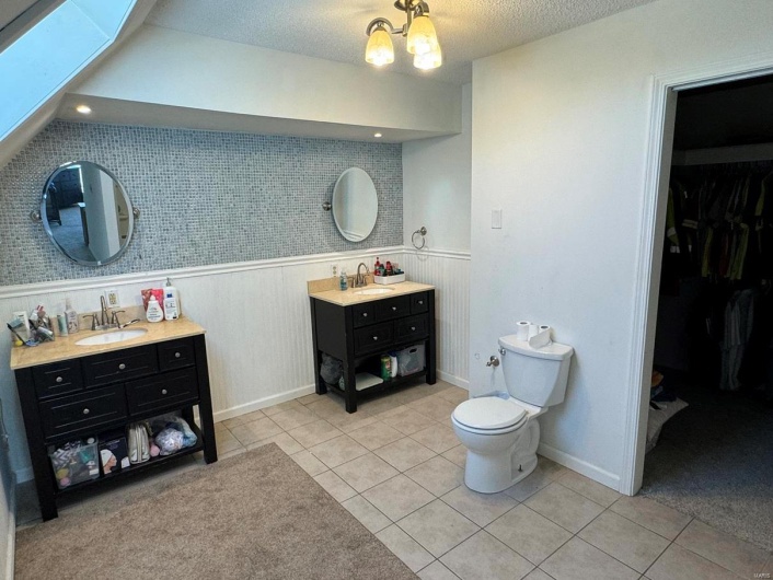 Full bath with tile patterned floors, a sink, and a wainscoted wall
