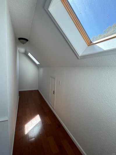 Bonus room with a textured ceiling, wood-type flooring, baseboards, and lofted ceiling with skylight